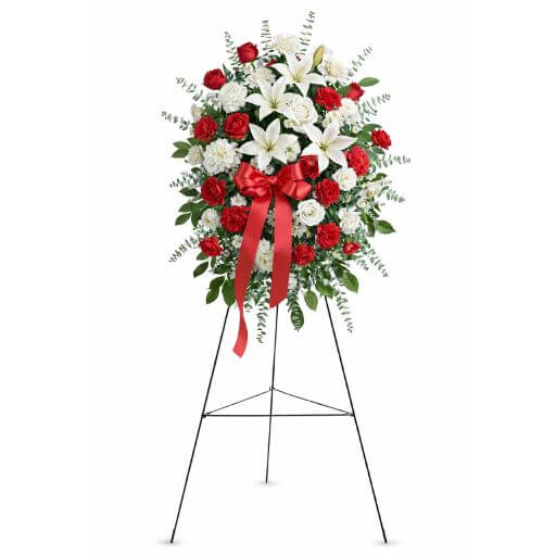 Floral arrangement with red and white flowers on a stand against a white background